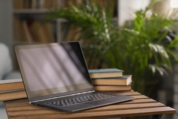 Laptop on table with books and plant